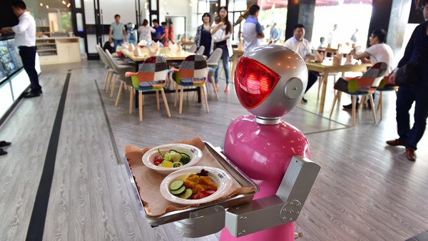 YIWU, CHINA - MAY 18: (CHINA OUT) A "female" robot waiter delivers meals for customers at robot-themed restaurant on May 18, 2015 in Yiwu, Zhejiang province of China. Sophomore Xu Jinjin in 22 years old from Hospitality Management of Yiwu Industrial and Commercial College managed a restaurant where a pair of robot acted as waiters. The "male" one was named "Little Blue" (for in blue color) and the "female" one was "Little Peach" (for in pink) and they could help order meals and then delivered them to customers along the magnetic track and said: "Here're your meals, please enjoy". According to Xu Jinjin, They had contacted with the designer to present more robot waiters to make the restaurant a real one that depends completely on robots. (Photo by ChinaFotoPress via Getty Images)
