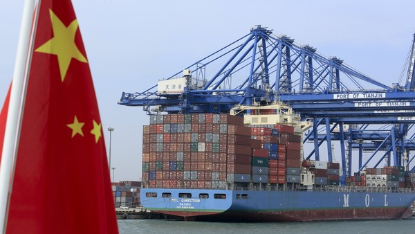 A Chinese flag flies on a vessel moving past shipping containers being unloaded at a Tianjin Port (Group) Co. Ltd. dock in Tianjin, China, on Wednesday, Sept. 12, 2012. The Chinese government is trying to meet a 7.5 percent economic growth target set in March, which would already be the weakest expansion since 1990. Photographer: Nelson Ching/Bloomberg