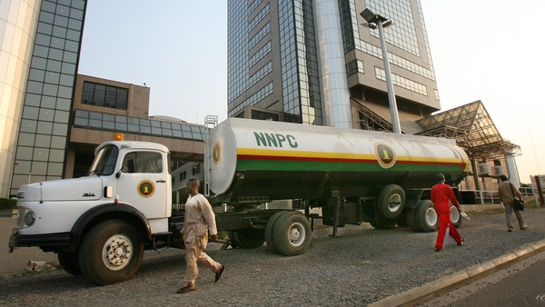 Men walk past a Nigerian National Petroleum Corporation tanker outside the NNPC headquarters in Abuja, Nigeria