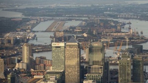 Aerial Views Of Canary Wharf And The City...Skyscrapers in the Canary Wharf business, financial and shopping district, including HSBC Holdings Plc, center left, One Canada Square, center, and Citigroup Inc., are seen in this aerial photograph, as London City airport, far left, and the Thames Barrier, far right, are seen in the background in London, U.K., on Tuesday, June 16, 2015. Britain had its smallest budget deficit for any May since 2007 as tax income jumped, handing a boost to Chancellor of the Exchequer George Osborne as he prepares to unveil the first budget of the new Conservative-only government. Photographer: Matthew Lloyd/Bloomberg