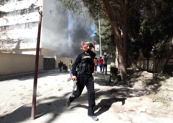 A fighter from the Islamist Syrian rebel group Jabhat al-Nusrah reacts as a picture is taken of him as their base is shelled in Raqqa province, eastern Syria, March 14, 2013
